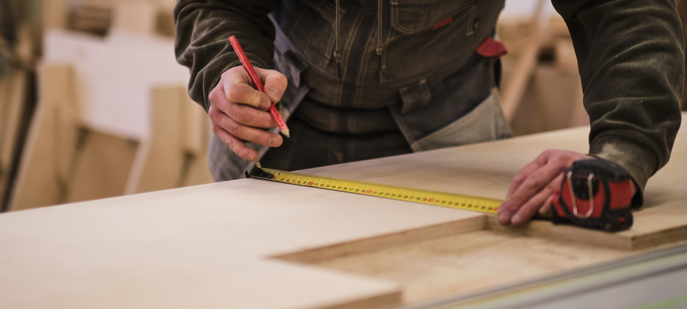 Carpenter measuring cabinet parts for ready-to-assemble construction