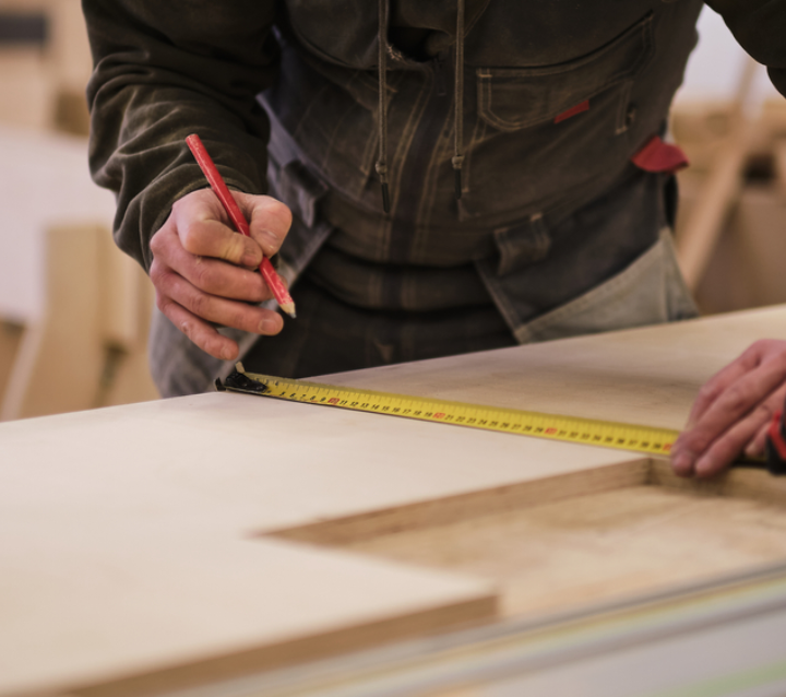 Carpenter measuring cabinet parts for ready-to-assemble construction