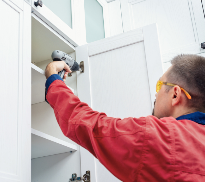 Worker using screwdriver to install kitchen cabinets